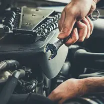 Hands and a wrench, over an open engine bay.